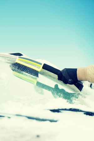 transportation, winter and vehicle concept - closeup of man cleaning snow from car windshield with brushの写真素材