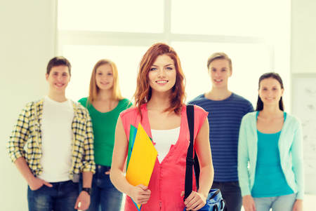 education and school concept - group of smiling students with teenage girl in front with bag and foldersの写真素材