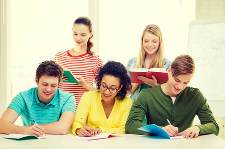 education and school concept - five smiling students with textbooks and books at schoolの写真素材