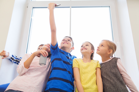 education, elementary school, drinks, children and people concept - group of school kids with smartphone and soda can taking selfie in corridorの写真素材