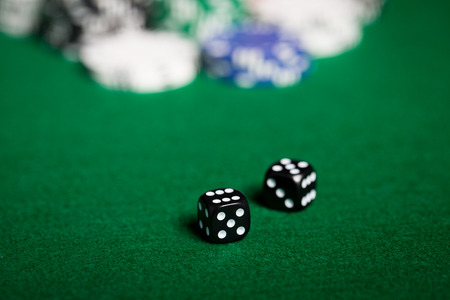 gambling, fortune, game and entertainment concept - close up of black dices on green casino table