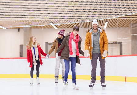 people, friendship, sport and leisure concept - happy friends on skating rinkの写真素材