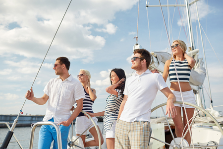 vacation, travel, sea, friendship and people concept - smiling friends sailing on yachtの写真素材