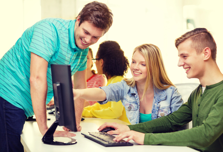 education, technology and school concept - smiling students in computer class at school