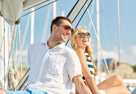 vacation, travel, sea, friendship and people concept - smiling couple sitting and talking on yacht deckの写真素材