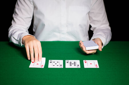 casino, gambling, poker, people and entertainment concept - close up of holdem dealer with playing...