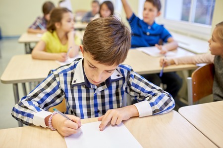 education, elementary school, learning and people concept - group of school kids with pens and...