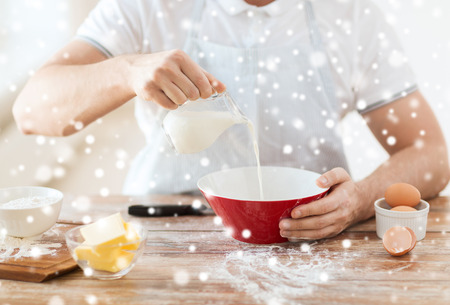 cooking, food, people and home concept - close up of man pouring milk into bowl and other ingredientsの写真素材