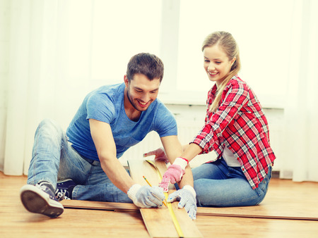 repair, building and home concept - smiling couple measuring wood flooringの写真素材