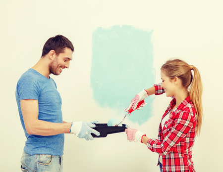repair, building and home concept - smiling couple painting wall at homeの写真素材