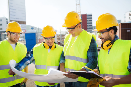 business, building, teamwork and people concept - group of smiling builders in hardhats with...
