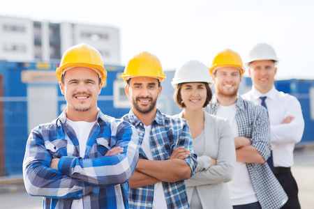 business, building, teamwork and people concept - group of smiling builders in hardhats outdoorsの写真素材