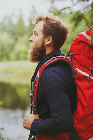 adventure, travel, tourism, hike and people concept - smiling man with beard and red backpack hikingの写真素材
