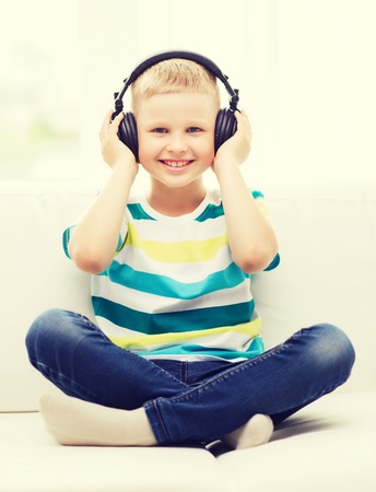 home, leisure, new technology, childhood and music concept - smiling little boy with headphones at homeの写真素材