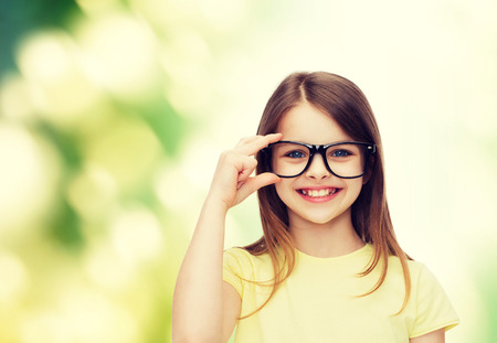 education, school and vision concept - smiling cute little girl in black eyeglassesの写真素材