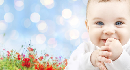 children, people, infancy and age concept - beautiful happy baby over blue lights and poppy field backgroundの写真素材