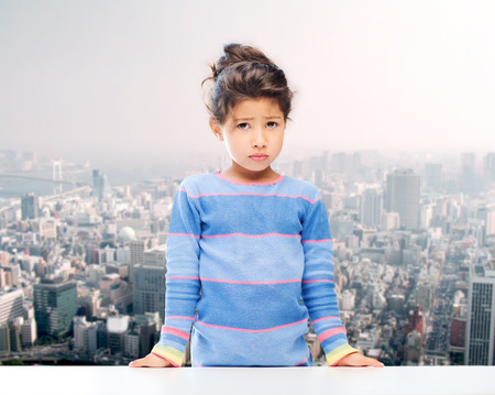 people, childhood and emotions concept - sad little girl over city backgroundの写真素材