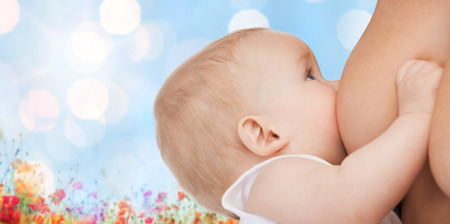 motherhood, children, people and care concept - close up of mother breast feeding adorable baby over blue sky with lights and poppy field backgroundの写真素材