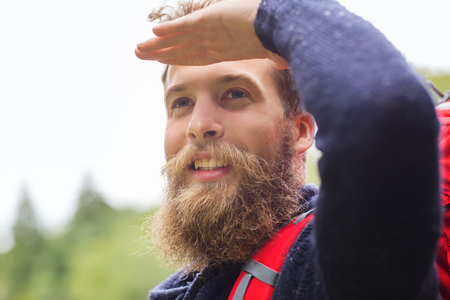 adventure, travel, tourism, hike and people concept - smiling man with beard and red backpack hikingの写真素材