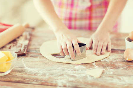 cooking and home concept - close up of female hands making cookies from fresh dough at homeの写真素材