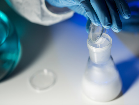 science, chemistry, biology, medicine and people concept - close up of scientist hand pouring...