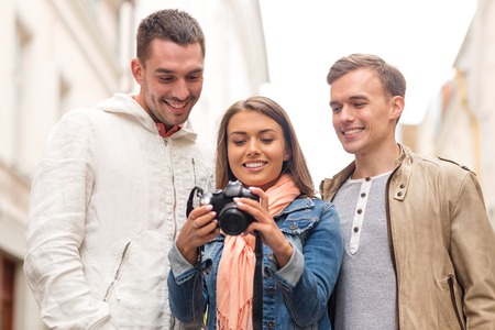 travel, vacation, technology and friendship concept - group of smiling friends with digital photocameraの写真素材