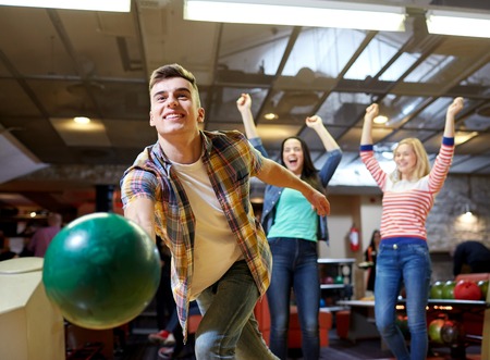 people, leisure, sport and entertainment concept - happy young man throwing ball in bowling club people, leisure, sport and entertainment concept - happy young man throwing ball in bowling club