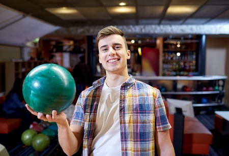 people, leisure, sport and entertainment concept - happy young man holding ball in bowling clubの写真素材