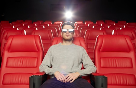 cinema, technology, entertainment and people concept - young man with 3d glasses watching movie alone in empty theater auditoriumの写真素材