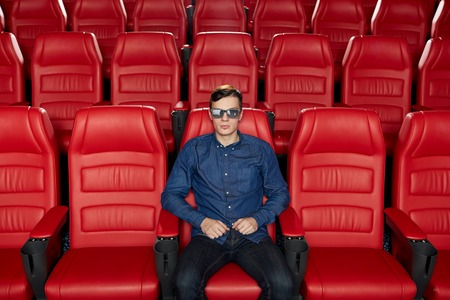 cinema, technology, entertainment and people concept - young man with 3d glasses watching movie alone in empty theater auditoriumの写真素材
