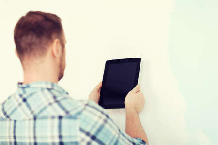 close up of male with tablet pc with blank screen next to painted wallの写真素材