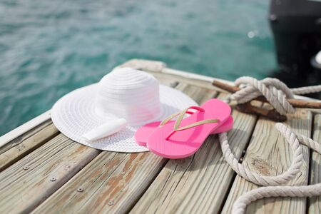 close up of hat, sunscreen and slippers at seaside