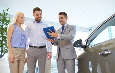 auto business, car sale, technology and people concept - happy couple with car dealer in auto show...