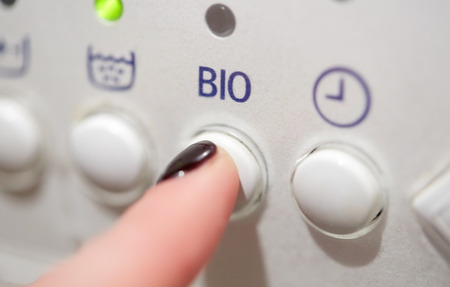 housework, laundry and housekeeping concept - close up of woman finger pressing washing machine...