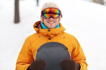winter, leisure, sport and people concept - happy young man in ski goggles outdoors