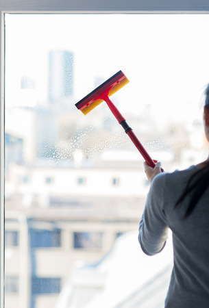 people, housework and housekeeping concept -close up of woman cleaning window with sponge mopの写真素材