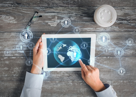 business, people, international communication and technology concept - close up of hands pointing finger to tablet pc computer screen with world map and internet contacts network on tableの写真素材