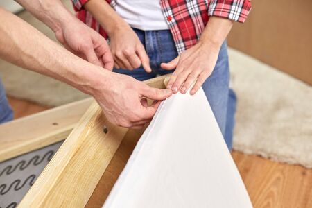 people, moving and furnishing concept - close up of couple assembling furniture at home
