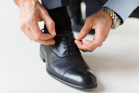 people, business, fashion and footwear concept - close up of man leg and hands tying shoe lacesの写真素材