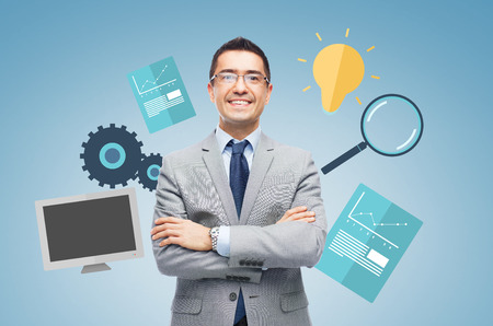 business, people, technology and development concept - happy smiling businessman in eyeglasses and suit over blue background and computer symbolsの写真素材