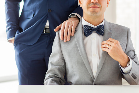 people, celebration, homosexuality, same-sex marriage and love concept - close up of male gay couple with wedding rings on putting hand on shoulderの写真素材