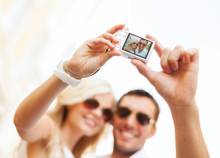 summer holidays, travel, vacation, tourism and dating concept - travelling couple taking photo picture with cameraの写真素材
