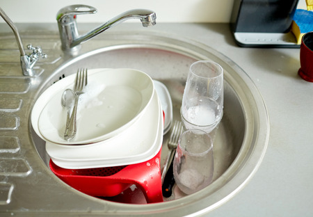 housework, washing-up and housekeeping concept - close up of dirty dishes washing in kitchen sinkの写真素材