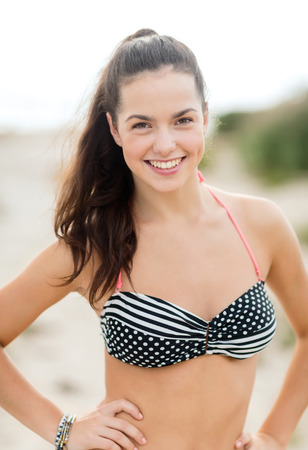 summer vacation, holidays and people concept - happy young woman in bikini swimsuit on beachの写真素材