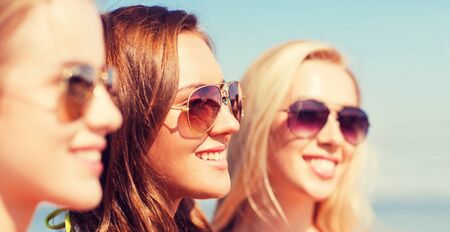 summer vacation, holidays, friendship and people concept - close up of smiling young women in sunglassesの写真素材