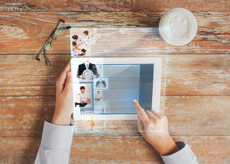 business, people, social network and technology concept - close up of hands pointing finger to tablet pc computer screen with internet article, coffee cup and eyeglasses on tableの写真素材