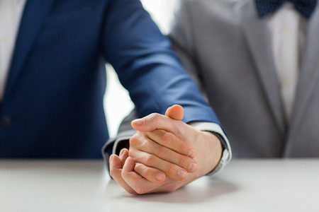 people, homosexuality, same-sex marriage and love concept - close up of happy male gay couple holding hands on weddingの写真素材