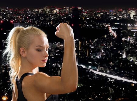 fitness and diet concept - close up of beautiful athletic woman flexing her bicepsの写真素材