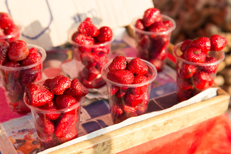food, sale and eating concept - strawberry in plastic cups at street market