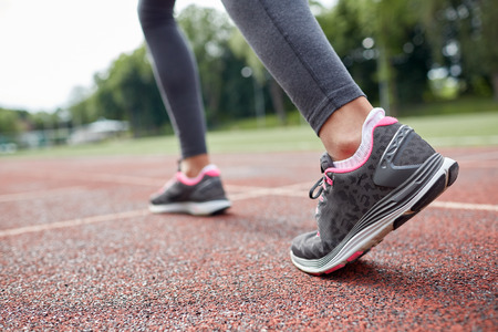 fitness, sport, training, people and lifestyle concept - close up of woman feet running on track from backの写真素材